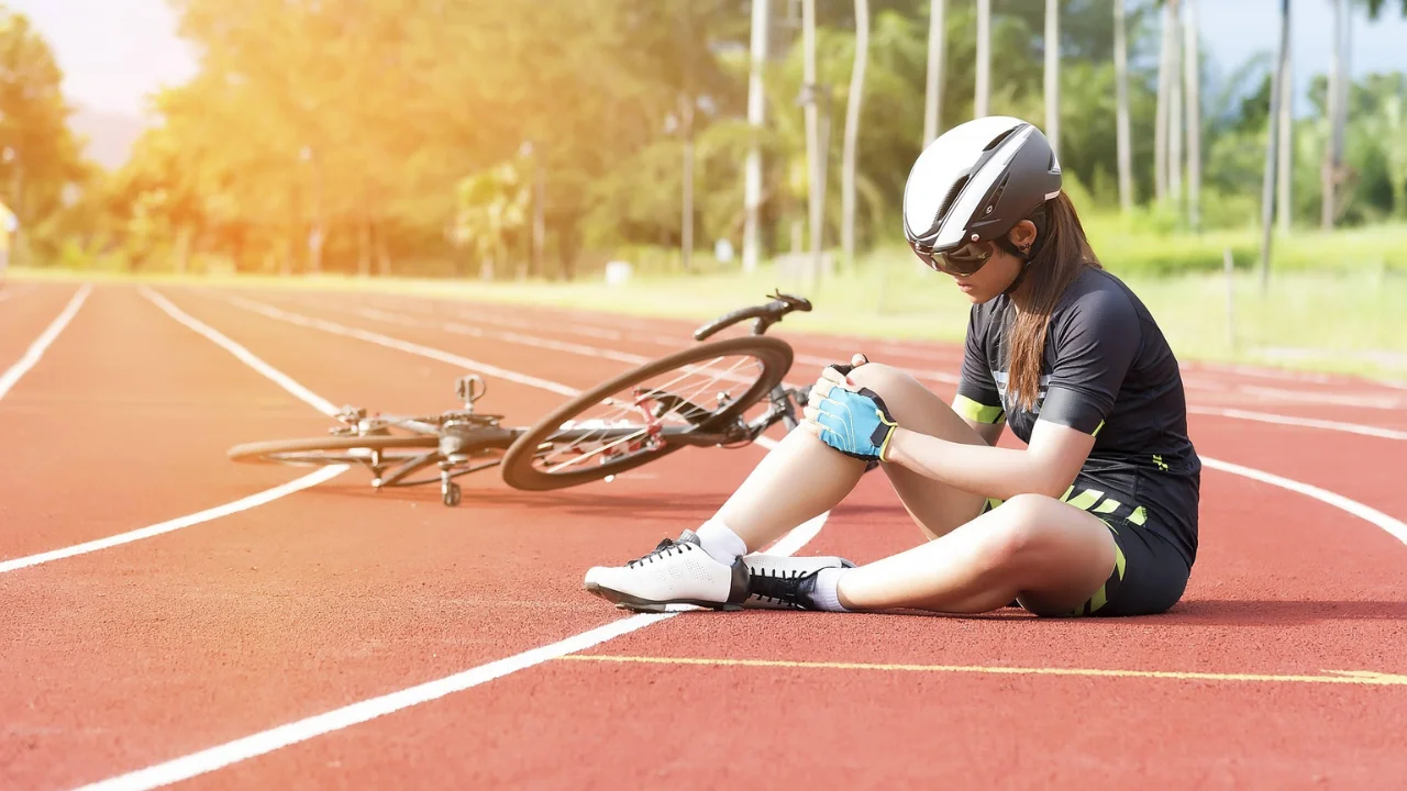 A woman beside a bicycle holding her leg in pain after an accident injury, in Dhaka