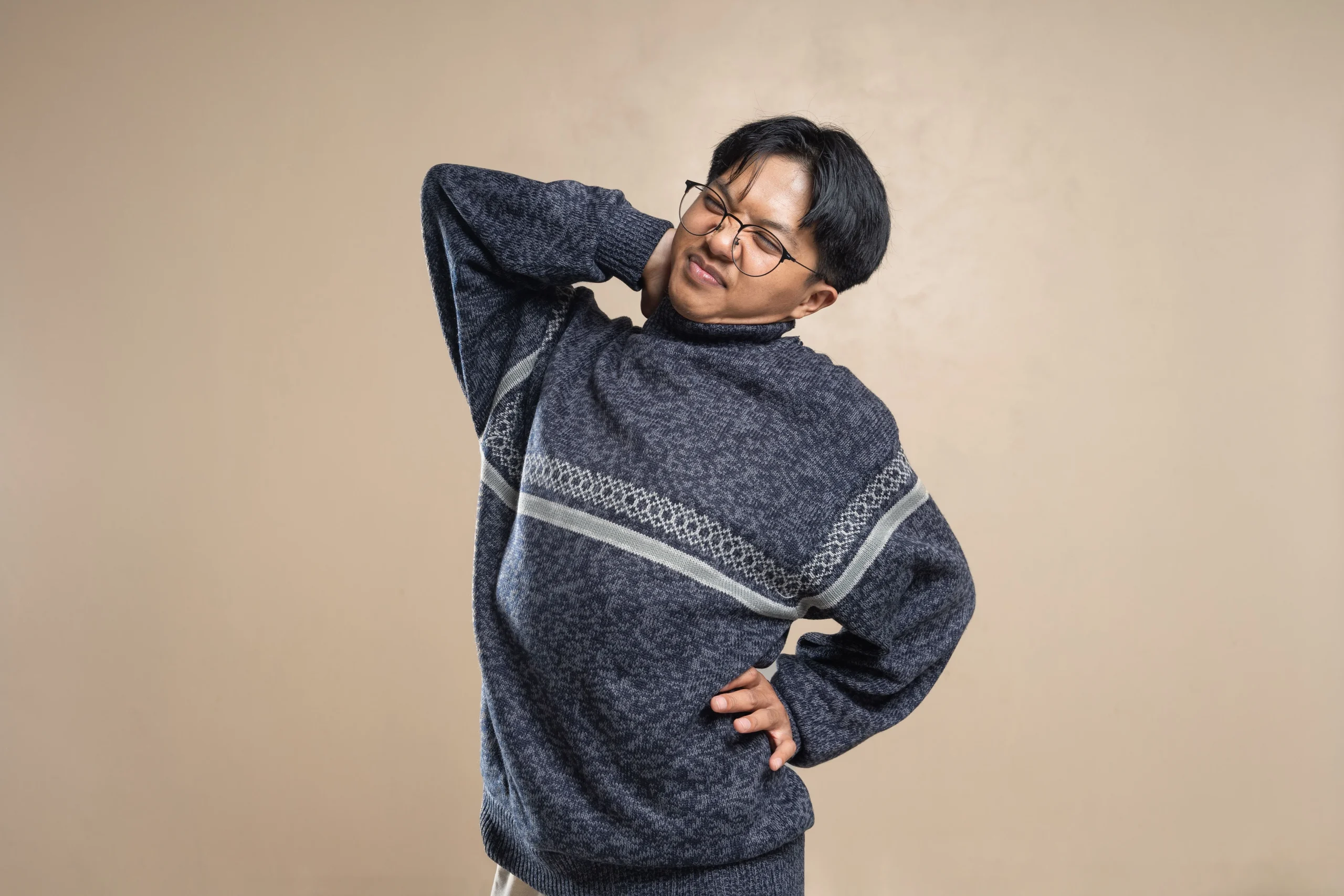 Adult South Asian person holding their lower back due to back pain at home